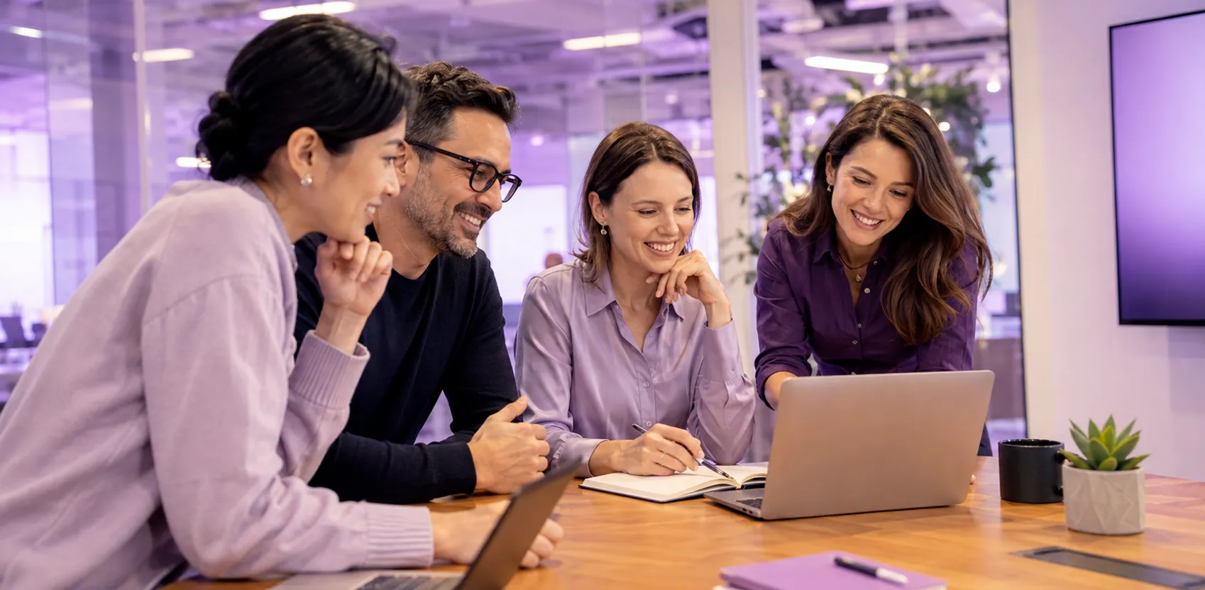 Four Anaptyss colleagues talking around a laptop in the office